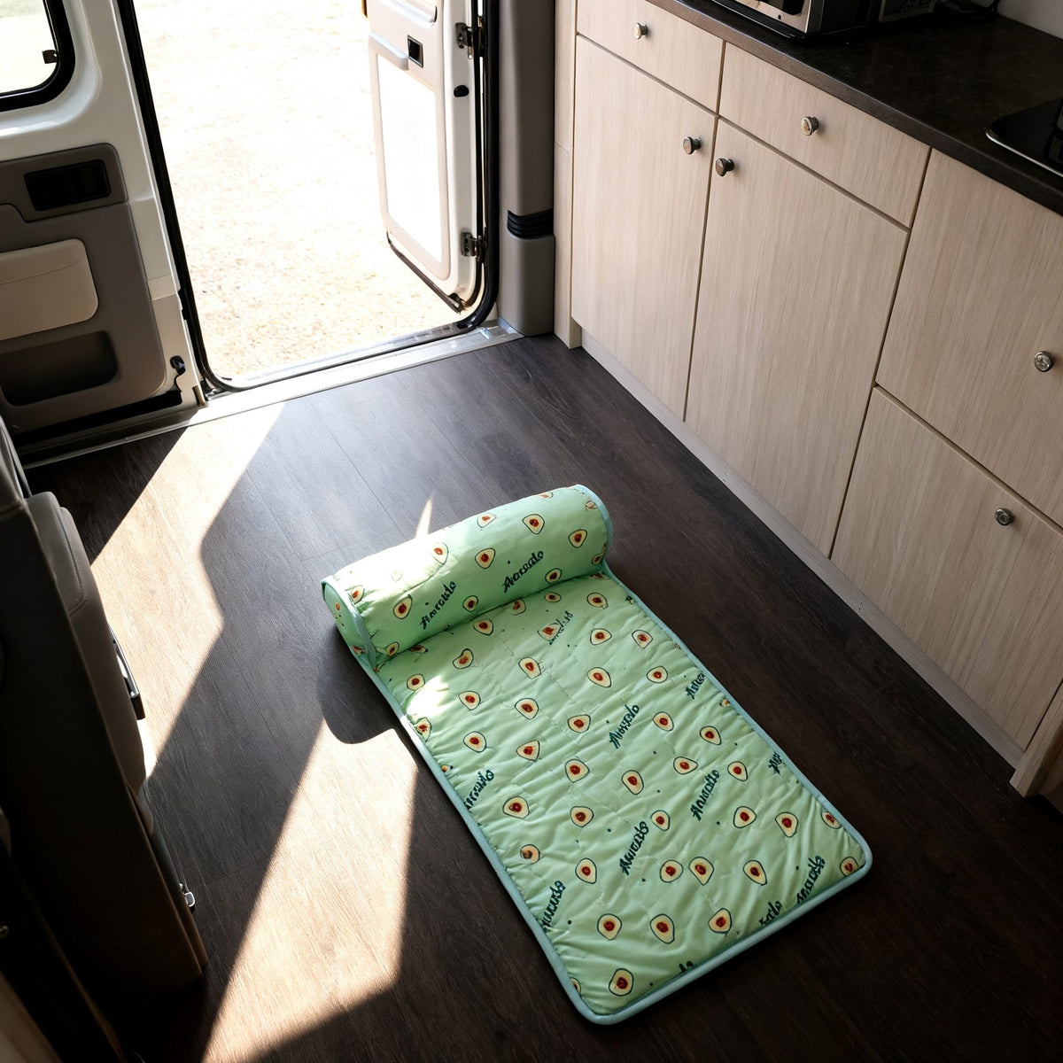 The bolster pet bed on the floor of a campervan beside the open side door