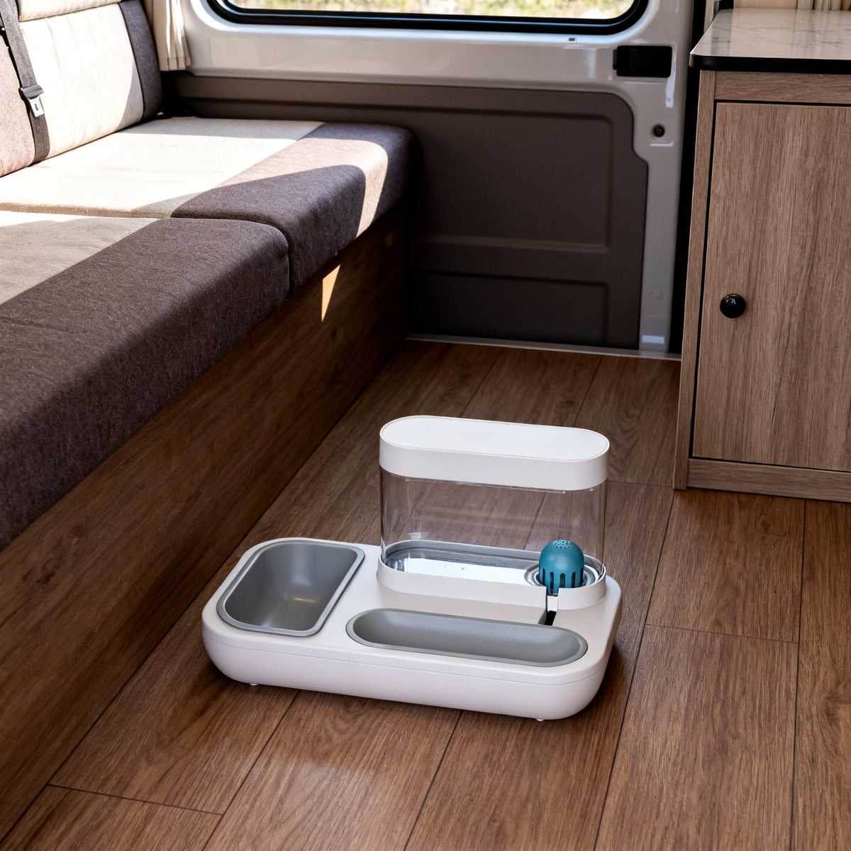 TrailPaw Auto Feeder on a camper van floor beside a dinette bench, showing its compact size