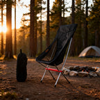 Black Heightened Moon Chair at a forest campsite beside a fire ring at golden hour